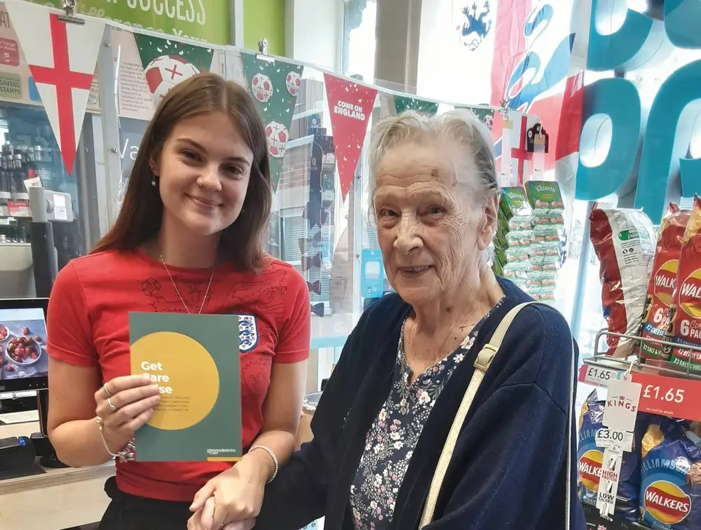 Volunteer and resident hold the “Get Care Wise” leaflet in a Greensleeves Care store