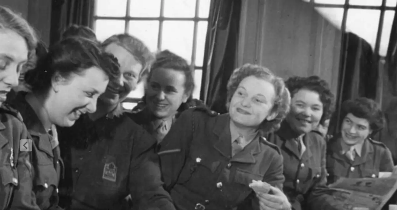 Smiling women celebrating VE Day in a care home, reflecting a legacy of care and social good