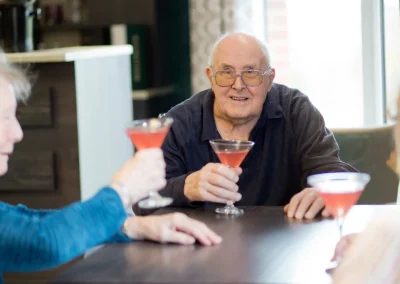 Residents enjoying a social gathering at Henley House Care Home, Ipswich – smiling individuals holding glasses in a friendly atmosphere