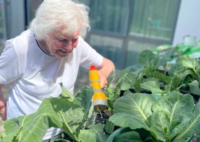 Resident watering plants in the garden at Clarendon Lodge Care Home