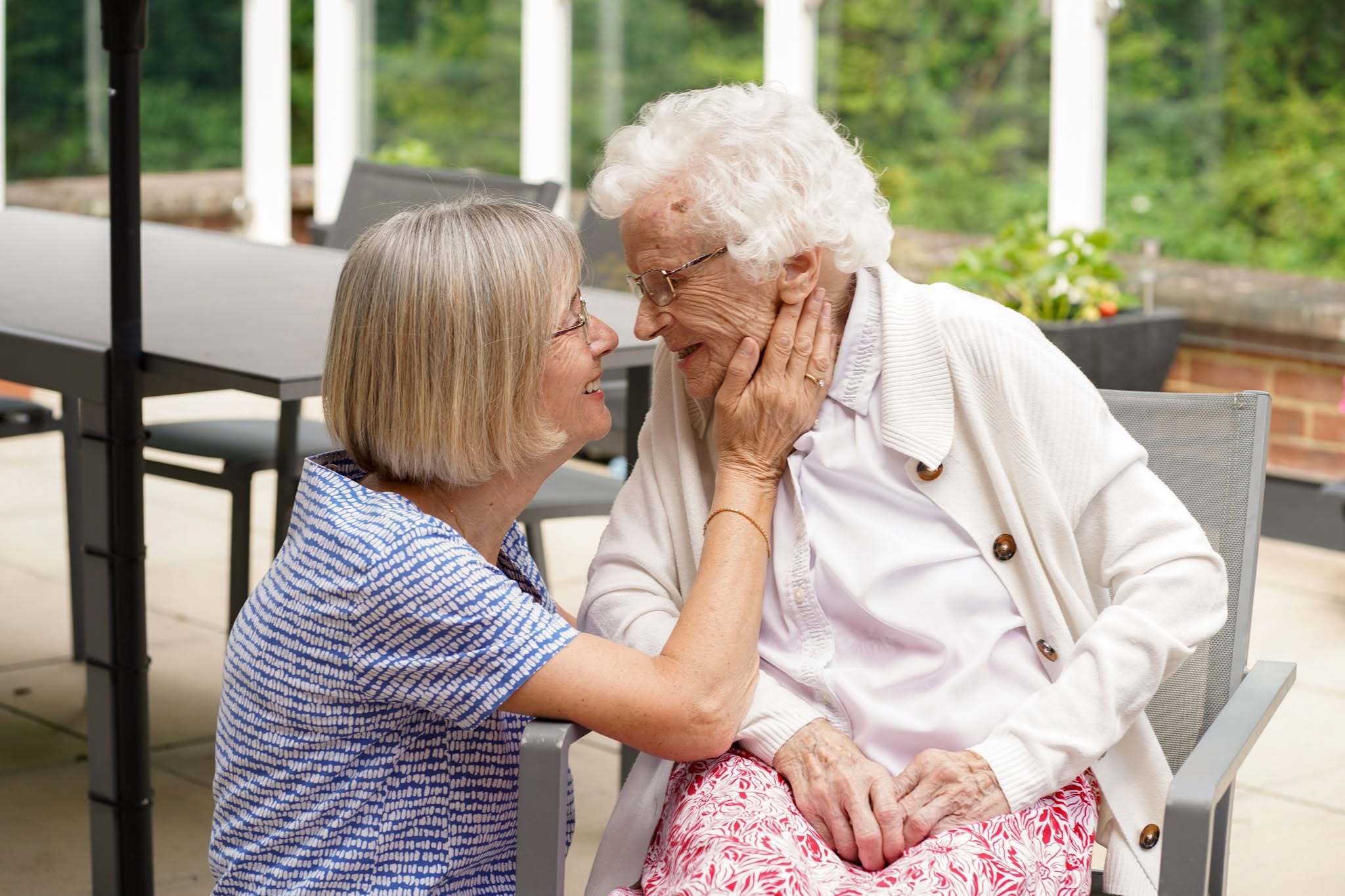 Caring gesture between caregiver and elderly woman outdoors