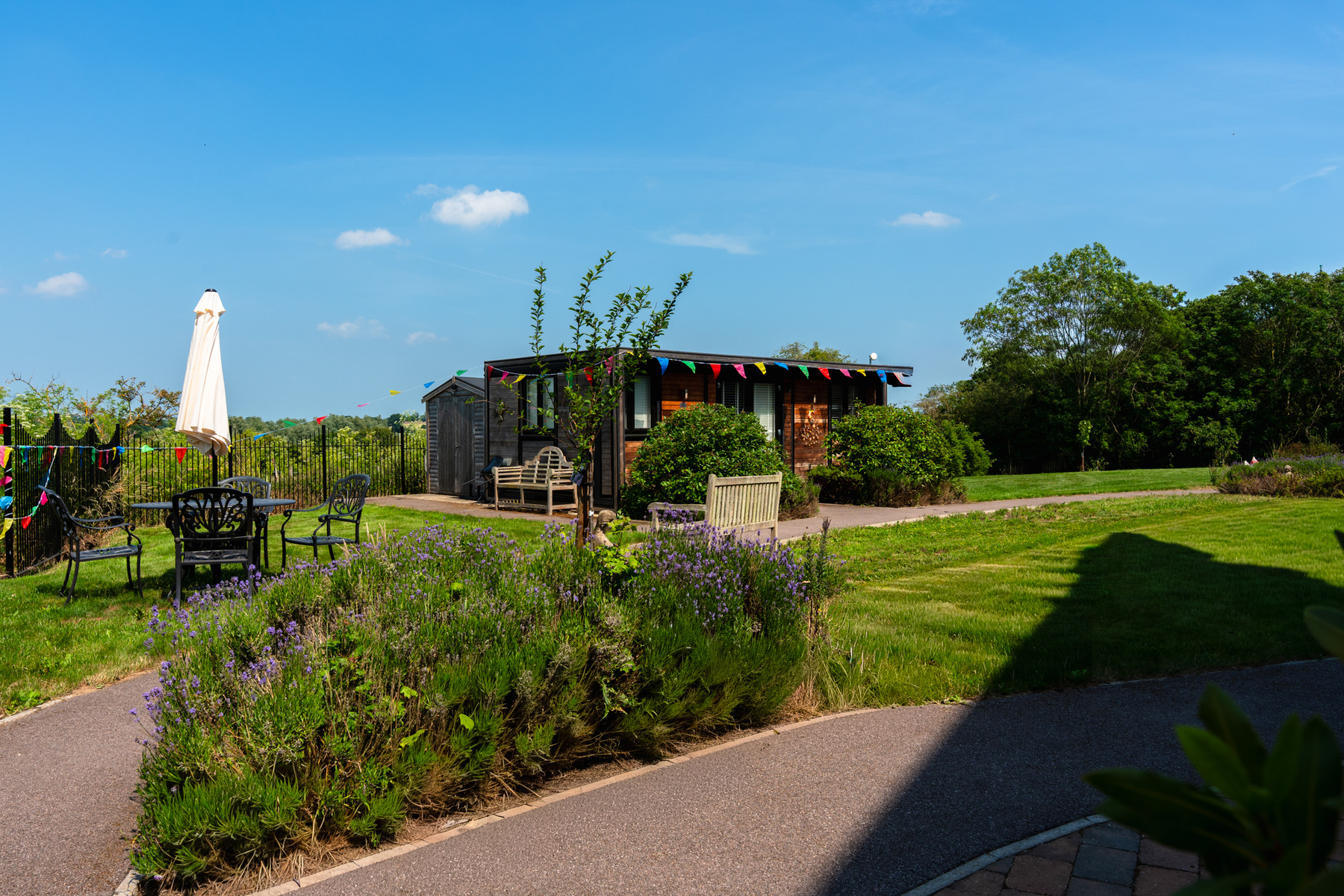Wooden garden cabin with colourful bunting, flowers and lawn at Henley House in Ipswich