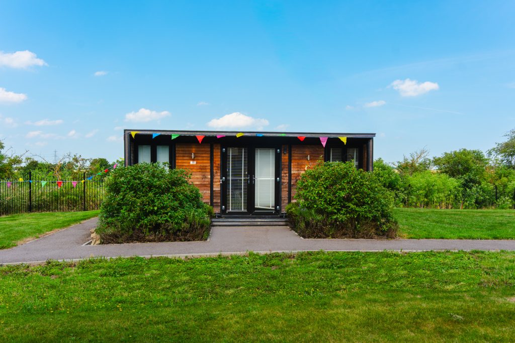 Modern wooden garden cabin with patio, greenery and bunting at Henley House in Ipswich