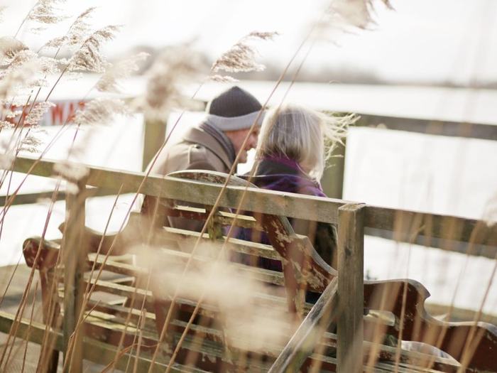 Two people talking together on a wooden bench
