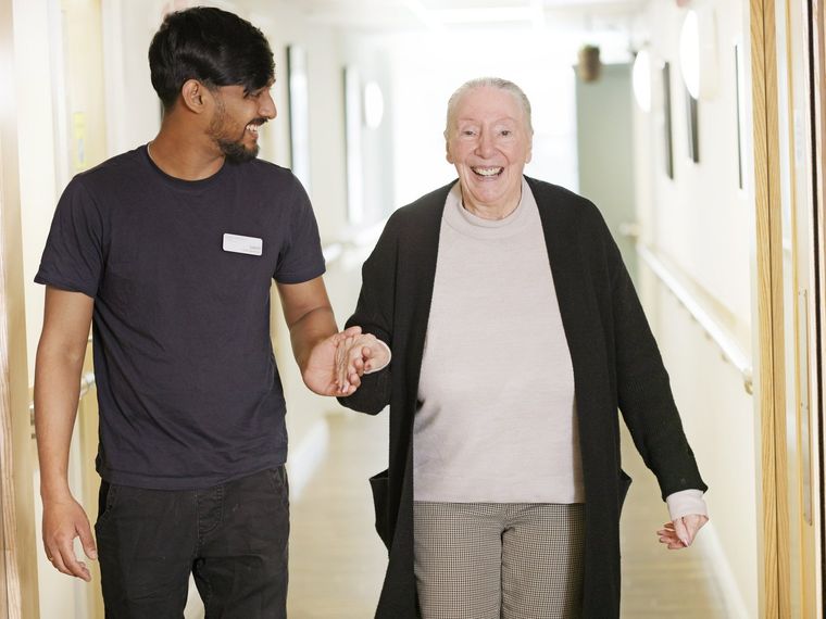 A Greensleeves Care colleague sitting with a resident, holding their hand
