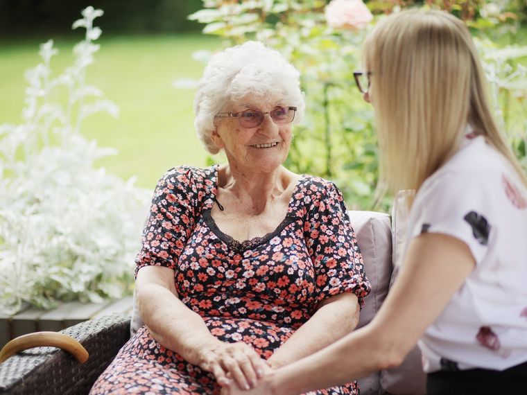 Two residents chatting together over tea in a bright communal room
