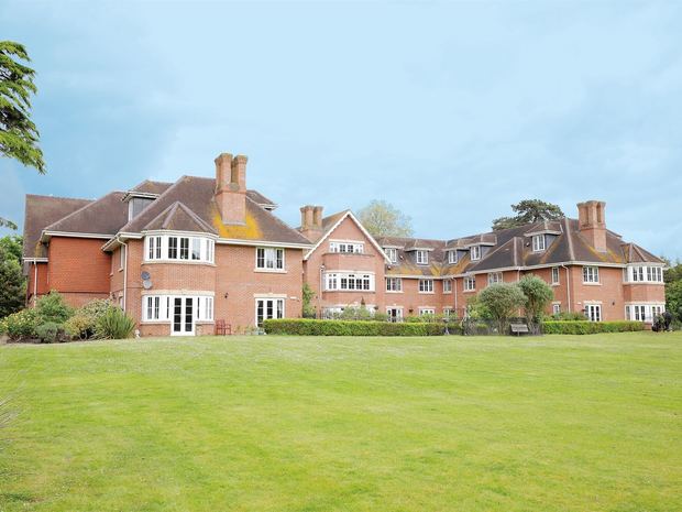 The red-brick exterior of a Greensleeves care home seen across its lawn